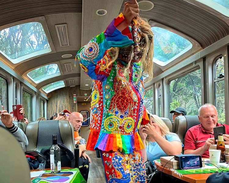 Turistas disfrutando espectáculo cultural dentro del tren panorámico durante el tour a Machu Picchu desde Cusco