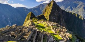 Vista panorámica de Machu Picchu con el sol iluminando las ruinas y montañas circundantes.